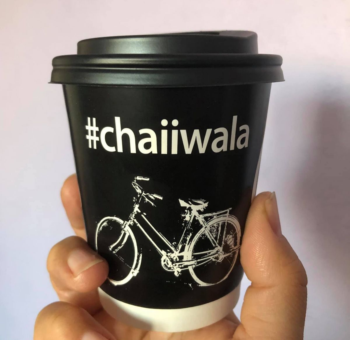holding a cup of tea with chaiiwala logo