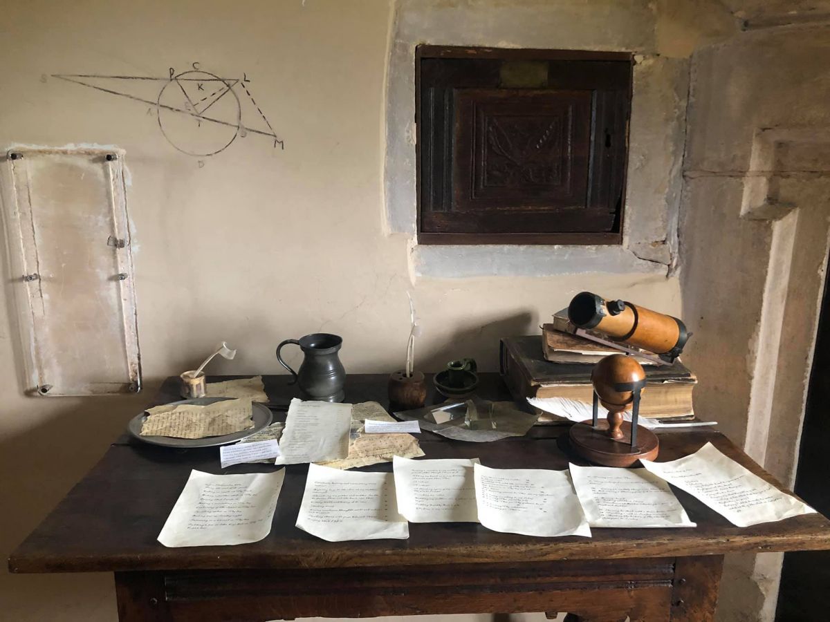 A desk where Isaac Newton did his work. Papers on the desk and writing on the wall