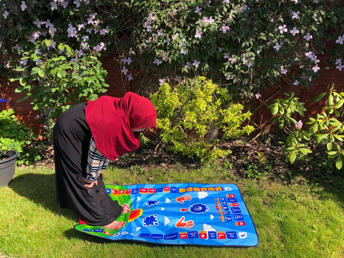 Child in garden praying on My Salah Mat